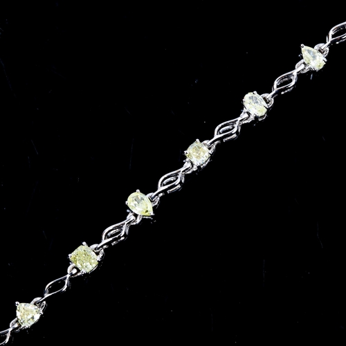 84 - A modern 18ct white gold fancy yellow diamond line bracelet, set with vari-cut yellow diamonds, incl... 