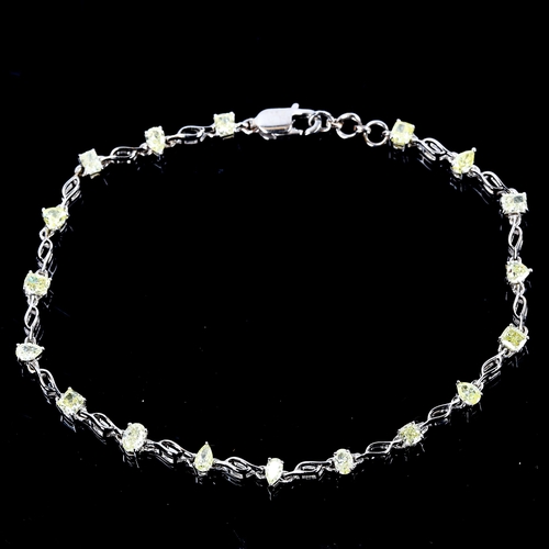 84 - A modern 18ct white gold fancy yellow diamond line bracelet, set with vari-cut yellow diamonds, incl... 