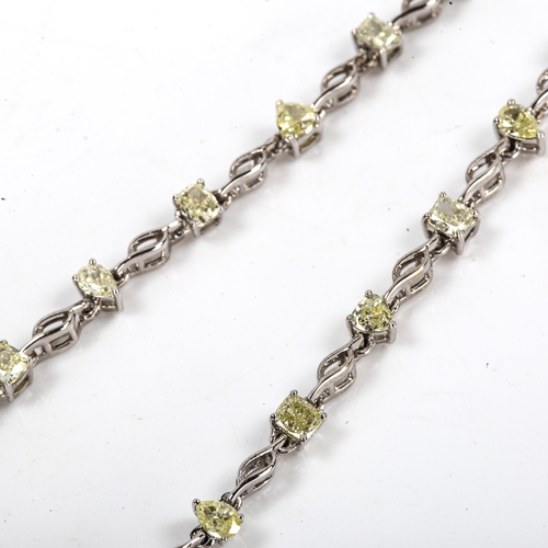 84 - A modern 18ct white gold fancy yellow diamond line bracelet, set with vari-cut yellow diamonds, incl... 