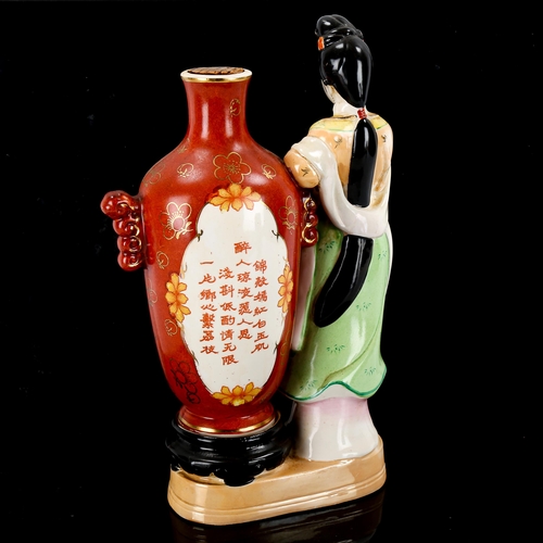 1090 - A bottle of Chinese Kaoliang Hung Chiew wine in sealed porcelain bottle, flanked by a figure of a wo... 