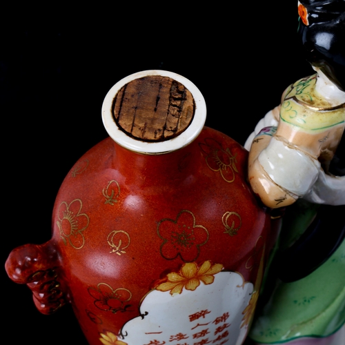 1090 - A bottle of Chinese Kaoliang Hung Chiew wine in sealed porcelain bottle, flanked by a figure of a wo... 