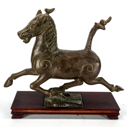 1204 - A Chinese patinated bronze sculpture of a running horse on wood plinth base, length 35cm