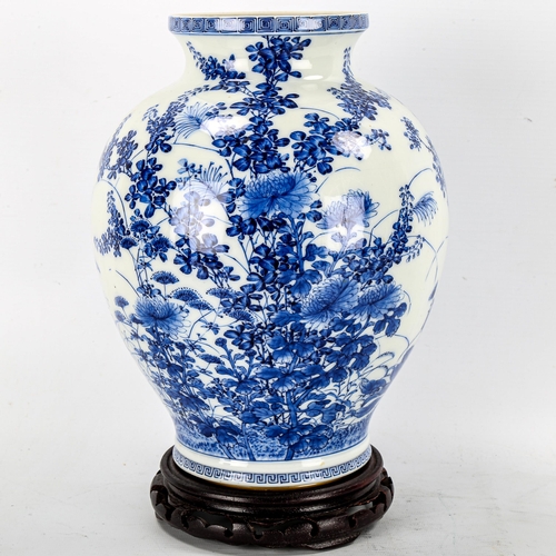 1245 - A Chinese blue and white porcelain vase with painted detailed floral design, attached wood base, hei... 