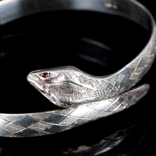 216 - A late 20th century silver and garnet figural snake hinged bangle, engraved decoration, by Fred Mans... 