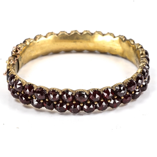 290 - A Victorian Bohemian faceted garnet bangle, unmarked yellow metal settings, band width 10.9mm, inter... 