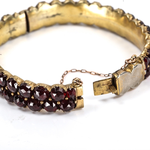 290 - A Victorian Bohemian faceted garnet bangle, unmarked yellow metal settings, band width 10.9mm, inter... 