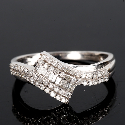 315 - A modern 9ct white gold diamond cluster crossover ring set with baguette and round brilliant-cut dia... 