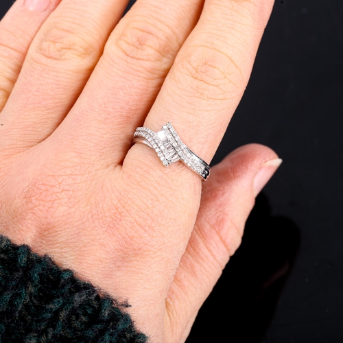 315 - A modern 9ct white gold diamond cluster crossover ring set with baguette and round brilliant-cut dia... 