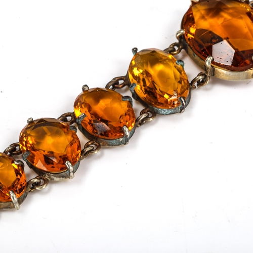 423 - An Edwardian graduated citrine line bracelet, unmarked white metal settings with oval mixed-cut citr... 