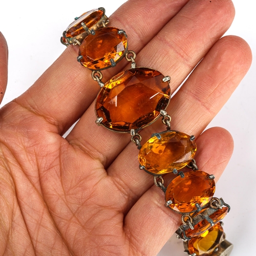 423 - An Edwardian graduated citrine line bracelet, unmarked white metal settings with oval mixed-cut citr... 