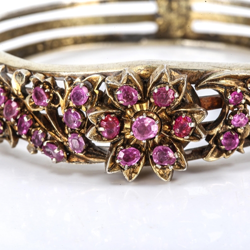 424 - A Victorian ruby floral hinged bangle, unmarked silver settings with pierced openwork decoration, se... 