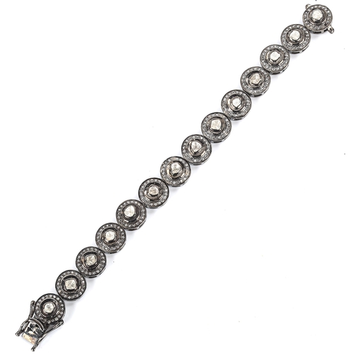 451 - A modern unmarked oxidised silver diamond cluster bracelet, set with table and rose-cut diamonds, to... 