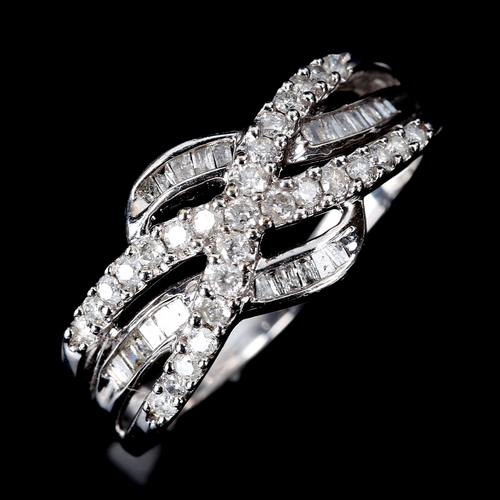 586 - A modern 9ct white gold diamond cluster crossover ring, set with modern round brilliant and baguette... 