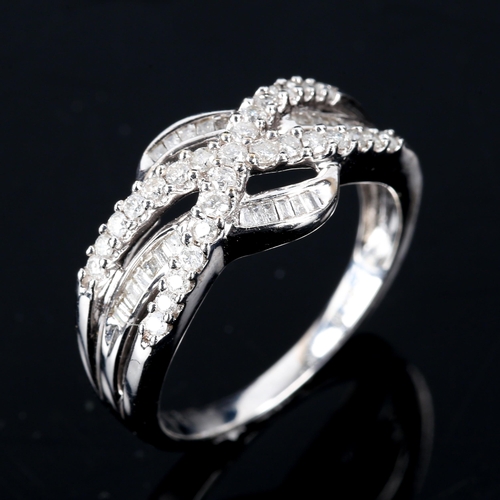 586 - A modern 9ct white gold diamond cluster crossover ring, set with modern round brilliant and baguette... 