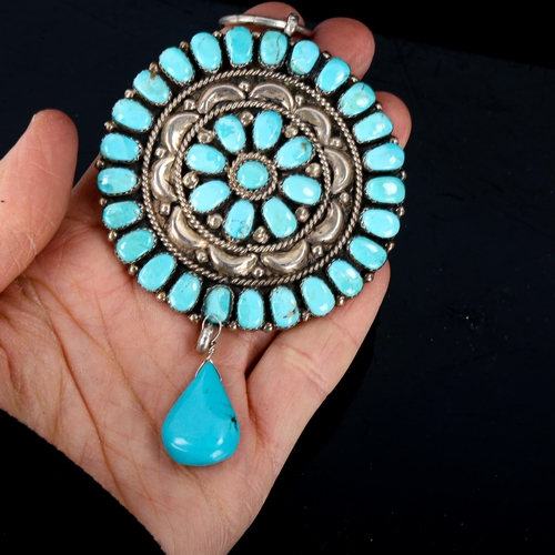 608 - A large Native American Navajo unmarked silver and turquoise pendant, relief embossed decoration wit... 