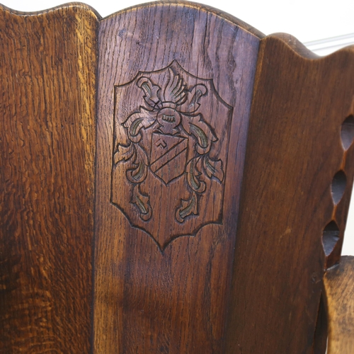 1152 - An oak-framed elbow chair, with carved armorial crest and rush seat, seat width 52cm