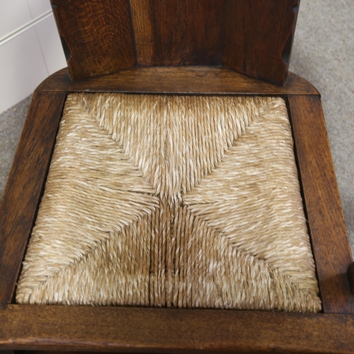 1152 - An oak-framed elbow chair, with carved armorial crest and rush seat, seat width 52cm