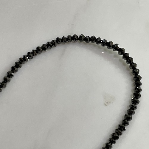 129 - A modern black diamond necklace, set with single-strand of faceted black diamond beads, with 14ct go... 