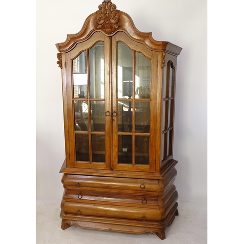 2194 - A Dutch style hardwood bookcase, of canted form, with glazed cupboard doors, and 3 graduated long dr... 