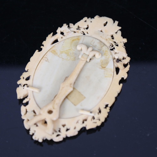 167 - A 19th century carved and pierced ivory oval photo frame, bird grapevine and acorn decoration, with ... 