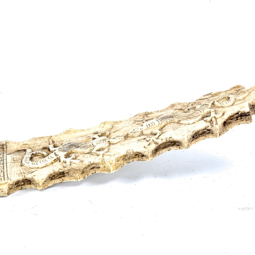 1120 - A 19th century Indonesian relief carved bone calendar, decorated with reptiles, length 42cm