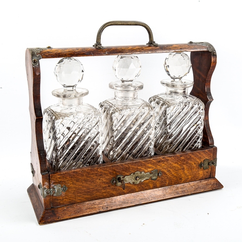 1154 - A Victorian oak 3-bottle tantalus, with electroplate mounts and 3 original decanters, length 34cm