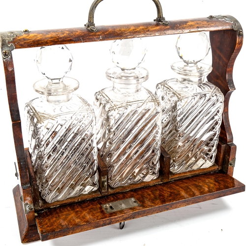 1154 - A Victorian oak 3-bottle tantalus, with electroplate mounts and 3 original decanters, length 34cm