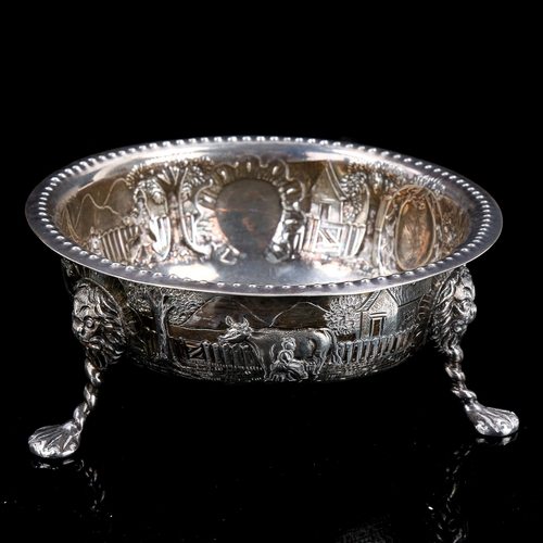 187 - An Edwardian Irish silver bowl, relief embossed farmyard scenes with lion mask and paw feet, by Samu... 