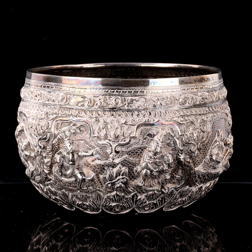 232 - A large early 20th century Burmese silver Thabeik rice bowl, high relief embossed figural deity deco... 