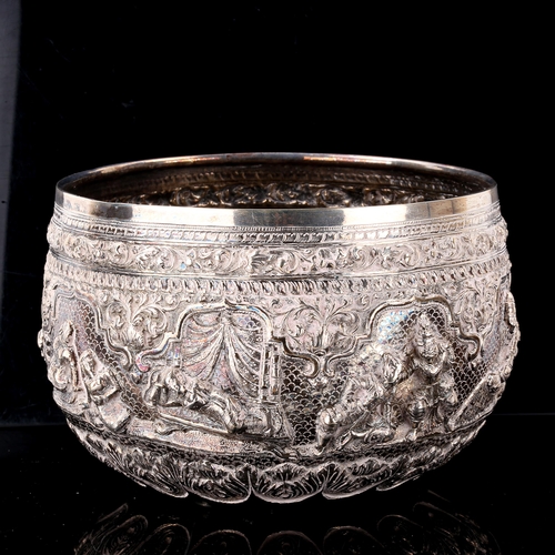 232 - A large early 20th century Burmese silver Thabeik rice bowl, high relief embossed figural deity deco... 