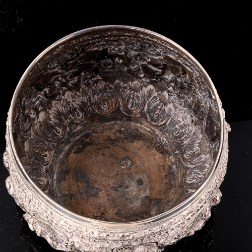 232 - A large early 20th century Burmese silver Thabeik rice bowl, high relief embossed figural deity deco... 