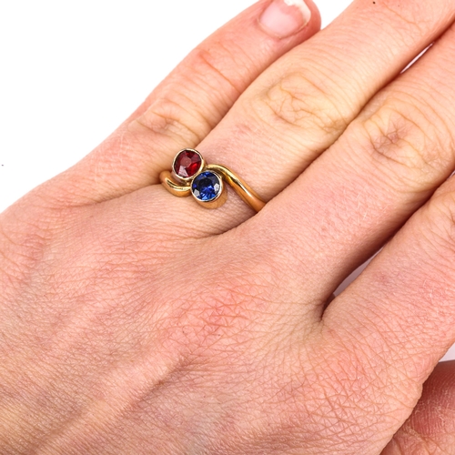 275 - An unmarked gold gem set crossover ring, set with red and blue stones, setting height 8.5mm, size N,... 