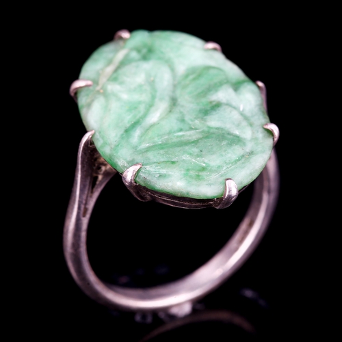 396 - A Chinese silver and carved jade oval panel ring, setting height 20.8mm, size J, 2.8g