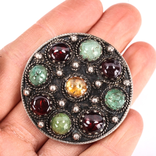 414 - An Arts and Crafts sterling silver gem set circular brooch, cannetille decoration with round cabocho... 