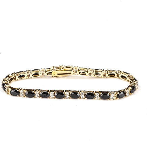 535 - A modern silver-gilt blue and white sapphire tennis line bracelet, bracelet length 18cm, 11.7g