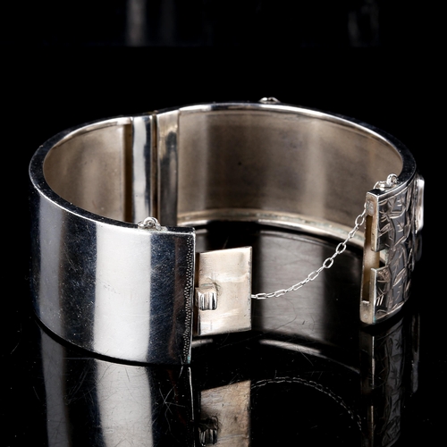 239 - An early 20th century silver buckle hinged bangle, engraved floral decoration, by Kenart Ltd, hallma... 