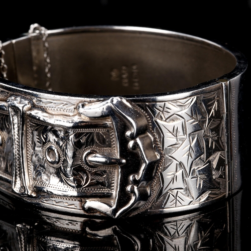 239 - An early 20th century silver buckle hinged bangle, engraved floral decoration, by Kenart Ltd, hallma... 