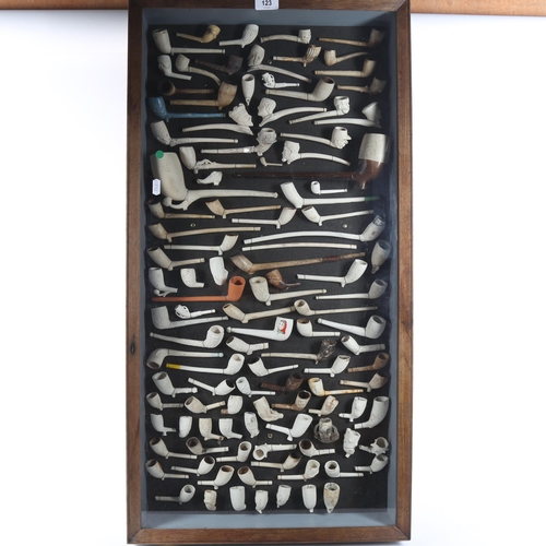 123 - A framed display of Antique clay pipes, including figural examples, 90cm x 46cm