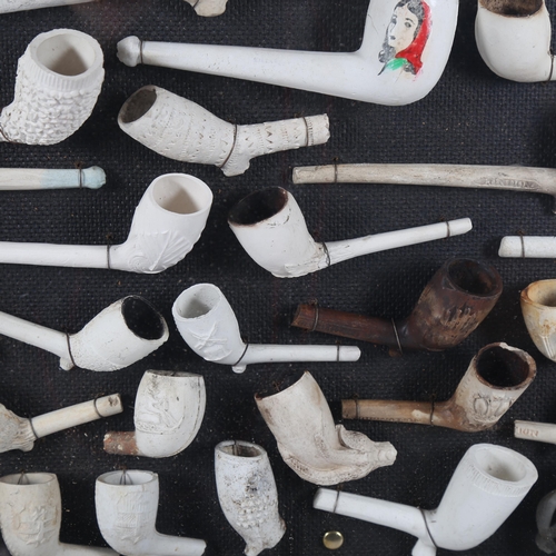 123 - A framed display of Antique clay pipes, including figural examples, 90cm x 46cm