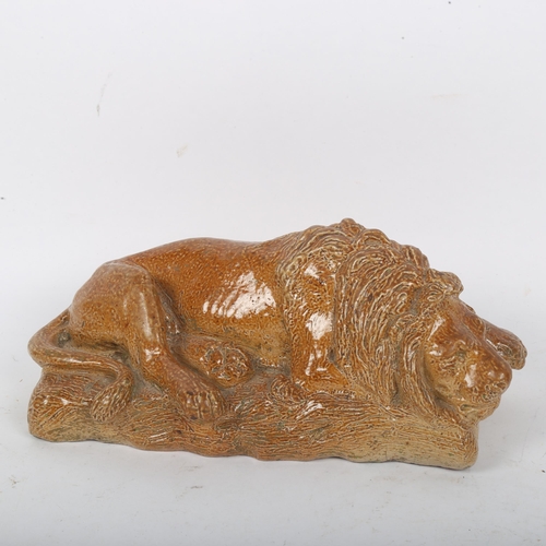 195 - A salt glaze stoneware pottery figural recumbent lion, indistinctly signed, length 20cm