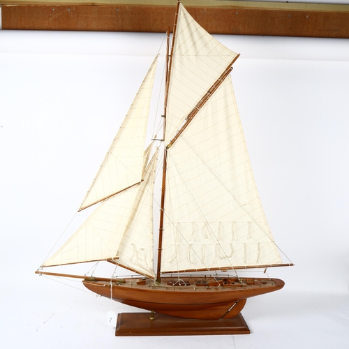 438 - Model wooden-hulled pond yacht, with sails and rigging, on fitted stand, overall height 94cm