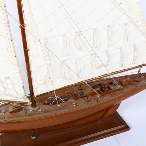 438 - Model wooden-hulled pond yacht, with sails and rigging, on fitted stand, overall height 94cm