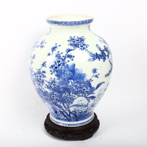 713 - A Chinese blue and white porcelain vase with painted detailed floral design, attached wood base, hei... 