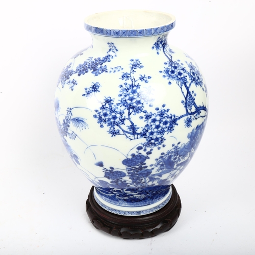 713 - A Chinese blue and white porcelain vase with painted detailed floral design, attached wood base, hei... 