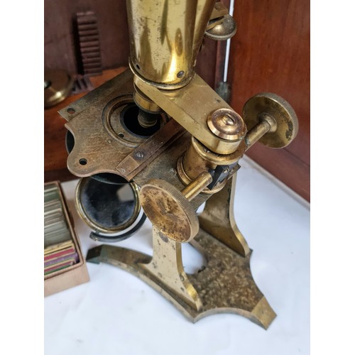 144A - A Victorian brass binocular microscope, with a box of slides and extra fittings, in original mahogan... 