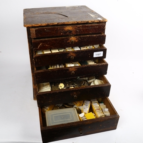 1107 - A Vintage watchmaker's table-top chest of drawers, containing a large quantity of various parts and ... 