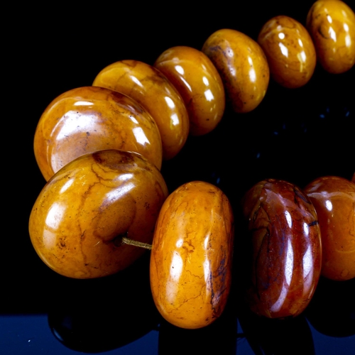 1127 - A string of large Tribal disc-shaped amber? beads, largest 6cm diameter