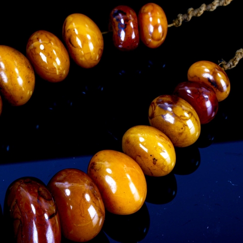 1127 - A string of large Tribal disc-shaped amber? beads, largest 6cm diameter