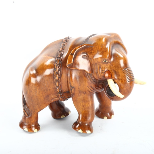 1258 - A well carved Indian honey coloured hardwood model of an elephant with chains and ivory tusks, heigh... 