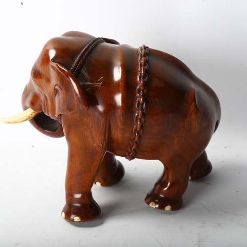 1258 - A well carved Indian honey coloured hardwood model of an elephant with chains and ivory tusks, heigh... 